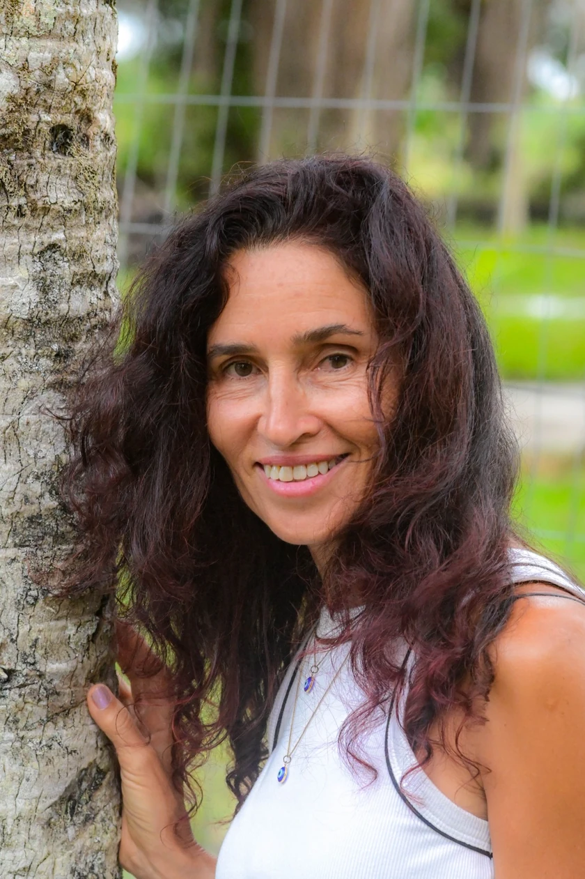 Retrato de Belkis sonriendo junto a un árbol
